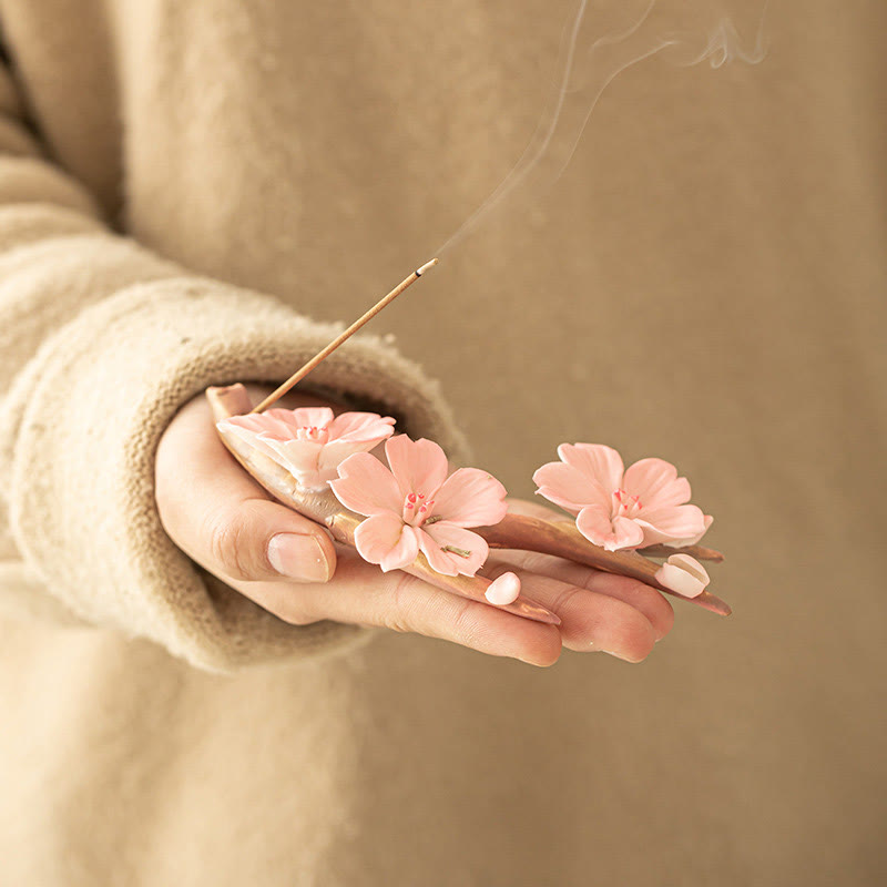 Plum Blossom Incense Burner – Handheld pink sakura holder with burning incense and loose petals, wellness