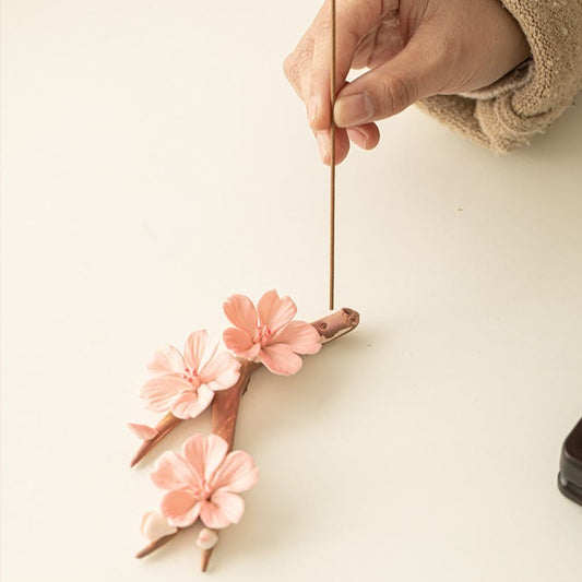 Plum Blossom Incense Burner – Hand placing stick into pink ceramic sakura flowers, incense holder