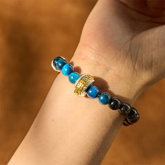 Om Mani Padme Hum Bracelet – Worn on wrist showing blue and black beads with gold charm, healing bracelet