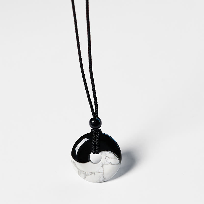 Obsidian White Turquoise Yin Yang Peace Buckle Necklace - Top-down view of black and white yin-yang donut pendant with adj...