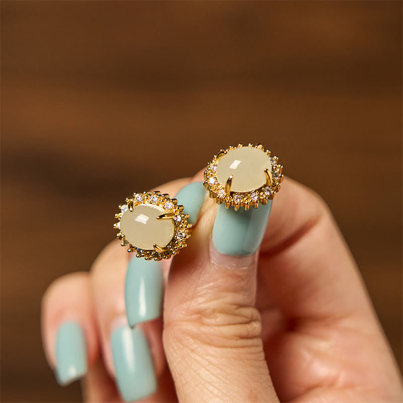 Hetian Jade Copper Earrings - held between fingers with pastel blue nails, warm bokeh, lifestyle
