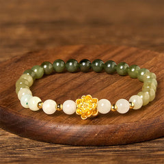 Hetian Jade Gradient Lotus Bracelet – full gradient beads on brown wood surface, gold flower center