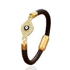 Brown braided leather evil eye bracelet with gold pave crystal charm on white background