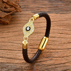 Espresso brown braided leather evil eye bracelet with gold crystal eye on weathered wood