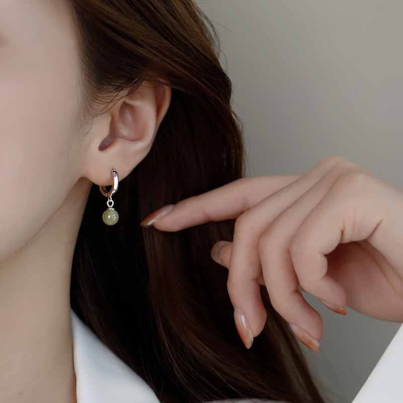 Round Jade Bead Prosperity Earrings – silver hoop with mint jade bead on ear with hand gesture, three-quarter profile lifestyle photo