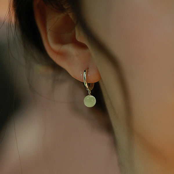 Round Jade Bead Prosperity Earrings – silver hoop with pale green jade bead worn on ear, side profile lifestyle macro shot