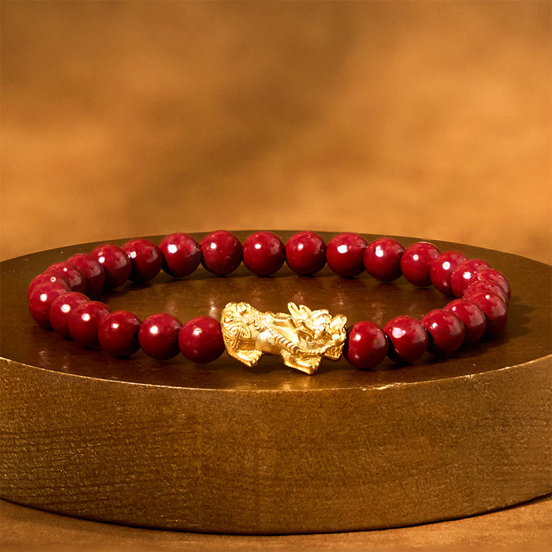 Natural Cinnabar Beads PiXiu Blessing Bracelet – gold PiXiu with red beads on round gold pedestal display, lucky bracelet