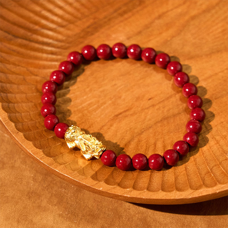 Natural Cinnabar Beads PiXiu Blessing Bracelet – gold PiXiu with red beads on carved wooden plate display, handmade jewelry