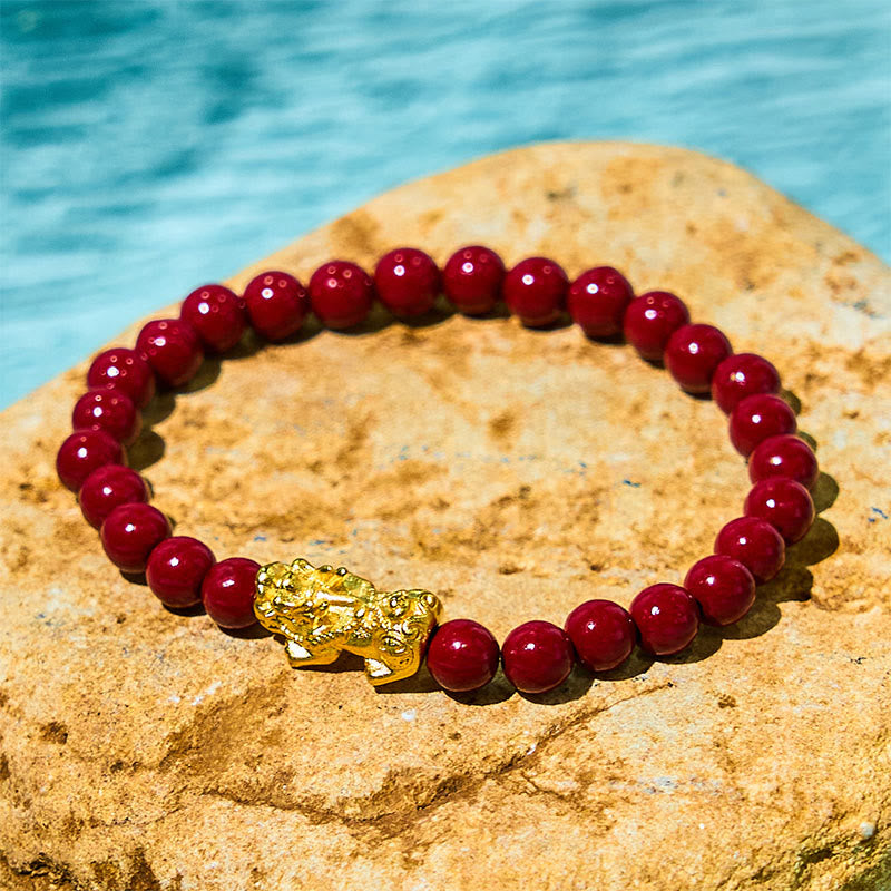 Natural Cinnabar Beads PiXiu Blessing Bracelet – gold PiXiu and red cinnabar beads on yellow rock waterside, wealth charm