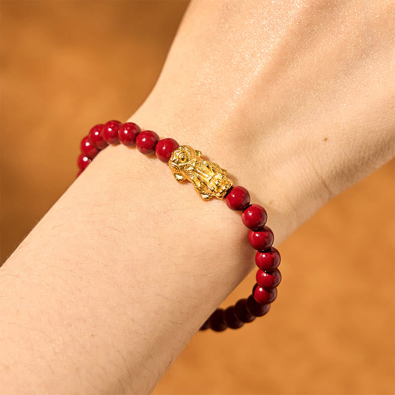 Natural Cinnabar Beads PiXiu Blessing Bracelet – wrist view with gold PiXiu and red beads on warm brown background, protection
