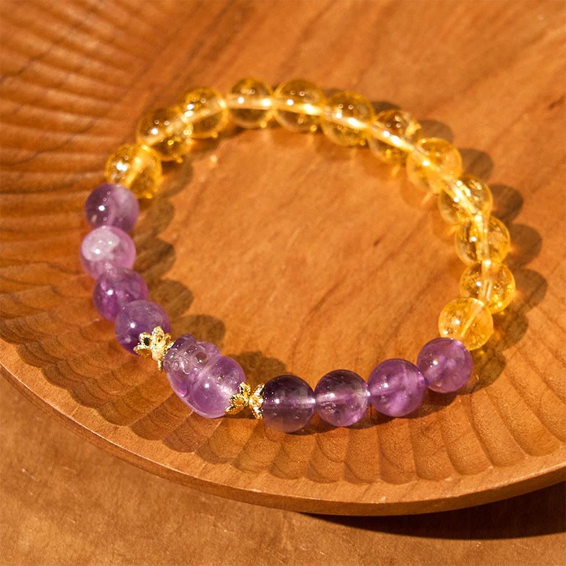 Citrine Amethyst PiXiu Prosperity Bracelet – purple PiXiu with citrine and amethyst beads on wooden plate, peace bracelet