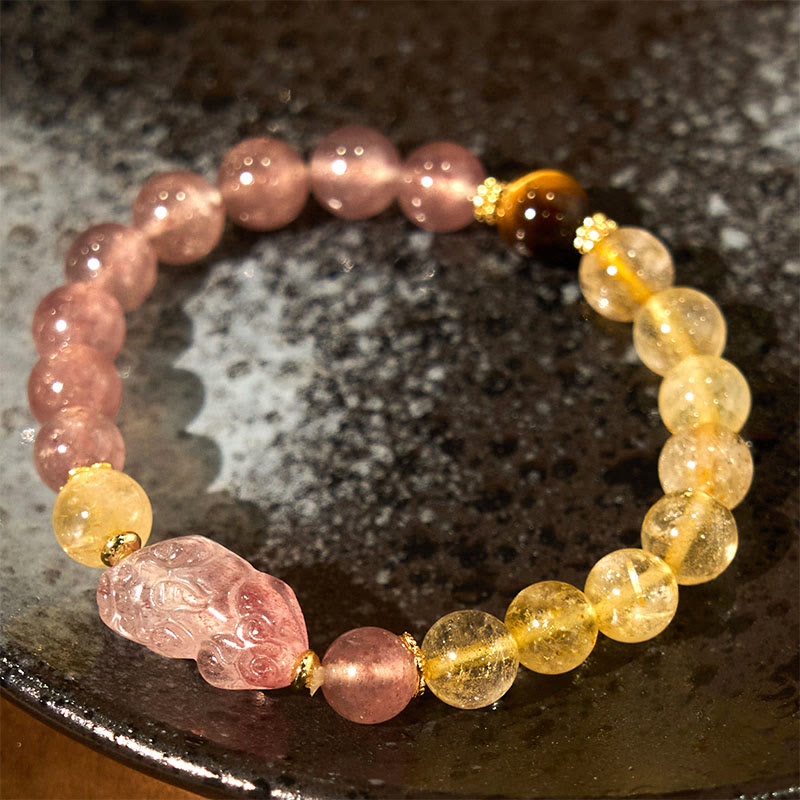 Strawberry Quartz PiXiu Rutilated Quartz Healing Bracelet – pink and gold beads with PiXiu on dark ceramic, wealth charm