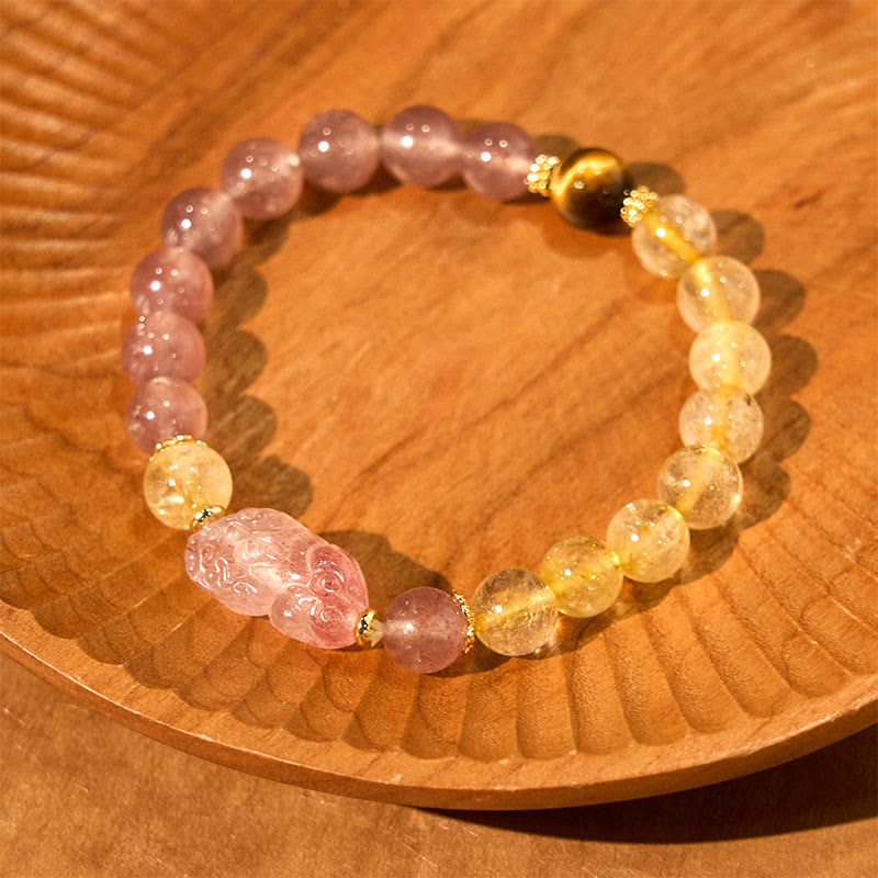 Strawberry Quartz PiXiu Rutilated Quartz Healing Bracelet – pink quartz PiXiu with gold beads on carved wooden plate display