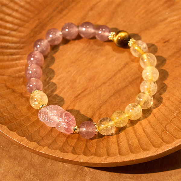 Strawberry Quartz PiXiu Rutilated Quartz Healing Bracelet – pink quartz PiXiu with gold beads on carved wooden plate display