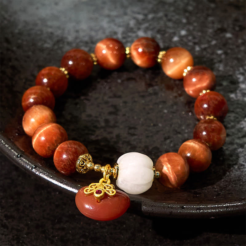 Red Tiger Eye Pumpkin Bracelet – On dark textured plate with red tiger eye beads and pumpkin charm, dramatic lighting