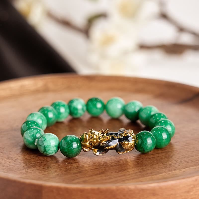 Feng Shui PiXiu Jade Protection Bracelet – Green jade bracelet with gold PiXiu on wooden tray, soft white floral background
