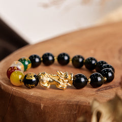 Gold Sheen Obsidian PiXiu Five Directions Gods of Wealth Bracelet – Side view with multi-color beads on wooden stump, feng shui