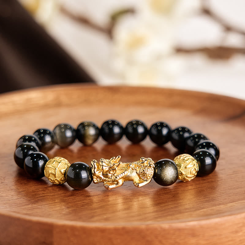 Gold Sheen Obsidian PiXiu Om Mani Padme Hum Wealth Bracelet – Gold PiXiu with obsidian beads on wooden tray, soft floral background