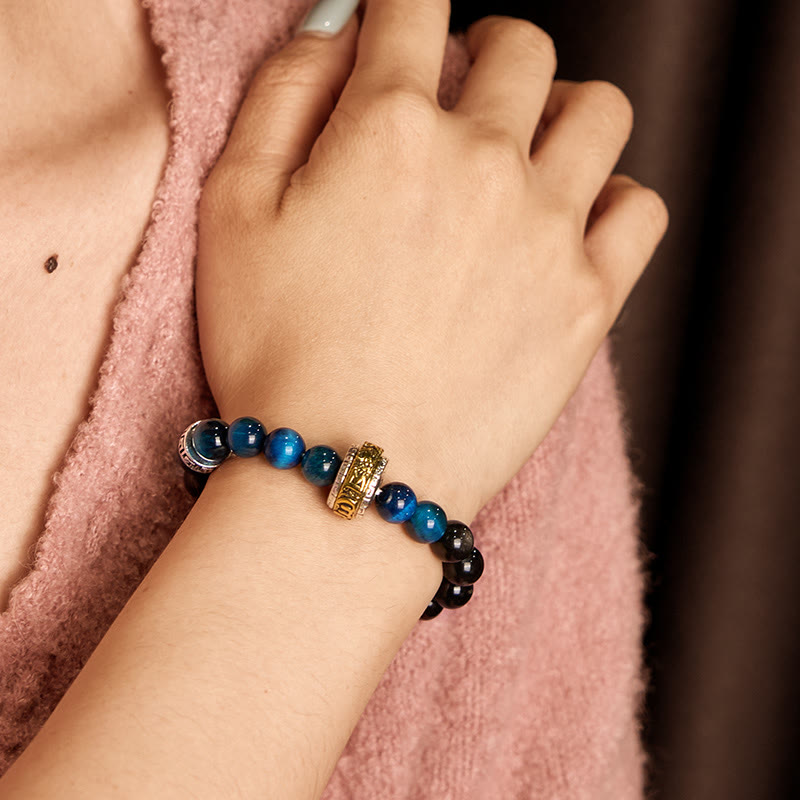 Om Mani Padme Hum Bracelet - Blue beads and gold charm on wrist against pink background, spiritual bracelet