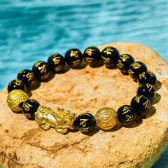 FengShui PiXiu Obsidian Bracelet – black obsidian mantra beads gold PiXiu on stone water background