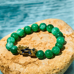 FengShui PiXiu Cyan Jade Bracelet – green jade beads gold PiXiu charm on stone water background, protection jewelry