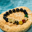 Obsidian PiXiu Five Gods Bracelet – Black obsidian with gold PiXiu and five colorful mantra beads on stone, water background
