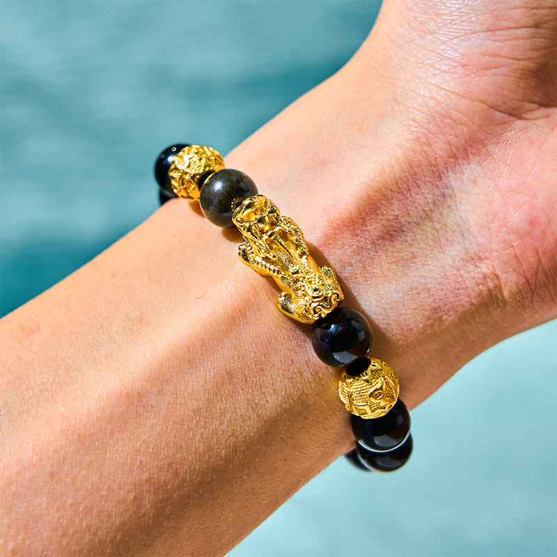 Gold Sheen Obsidian PiXiu Bracelet – Worn on wrist with black obsidian beads and gold PiXiu charm, turquoise water background