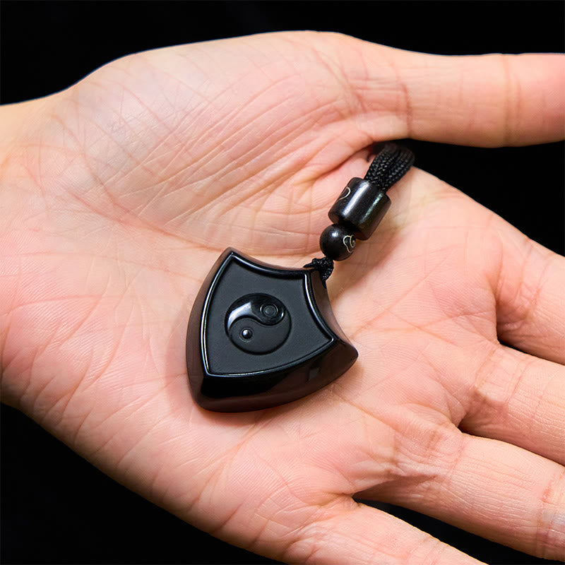 Black Obsidian Shield Pattern Yin Yang Streng - Polished obsidian yin-yang pendant in open palm, scale reference photo