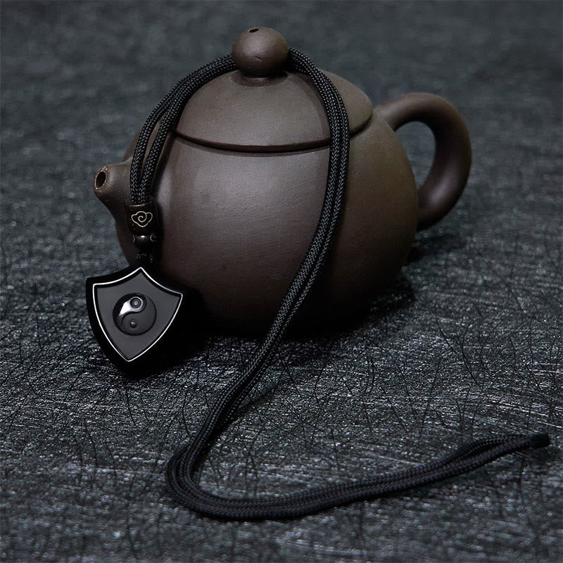 Black Obsidian Shield Pattern Yin Yang Streng - Obsidian shield pendant with yin-yang beside Yixing teapot, cultural styling