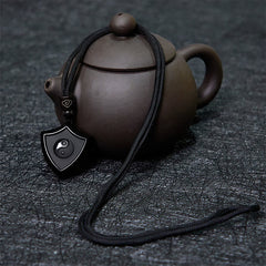 Black Obsidian Shield Pattern Yin Yang Streng - Obsidian shield pendant with yin-yang beside Yixing teapot, cultural styling