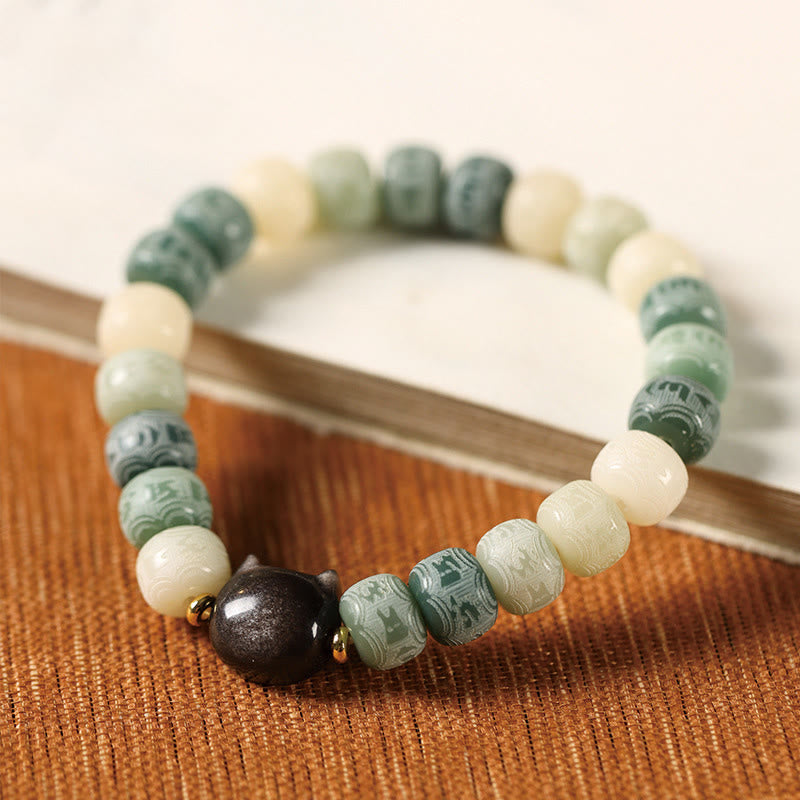 Bodhi Seed Silver Sheen Obsidian Cat Head Wisdom Bracelet – green variant side angle on wood, serene charm