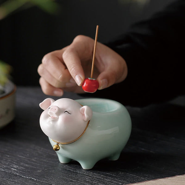 Ceramic Little Pig Incense Burner – Hand placing red incense stick into mint green pig holder