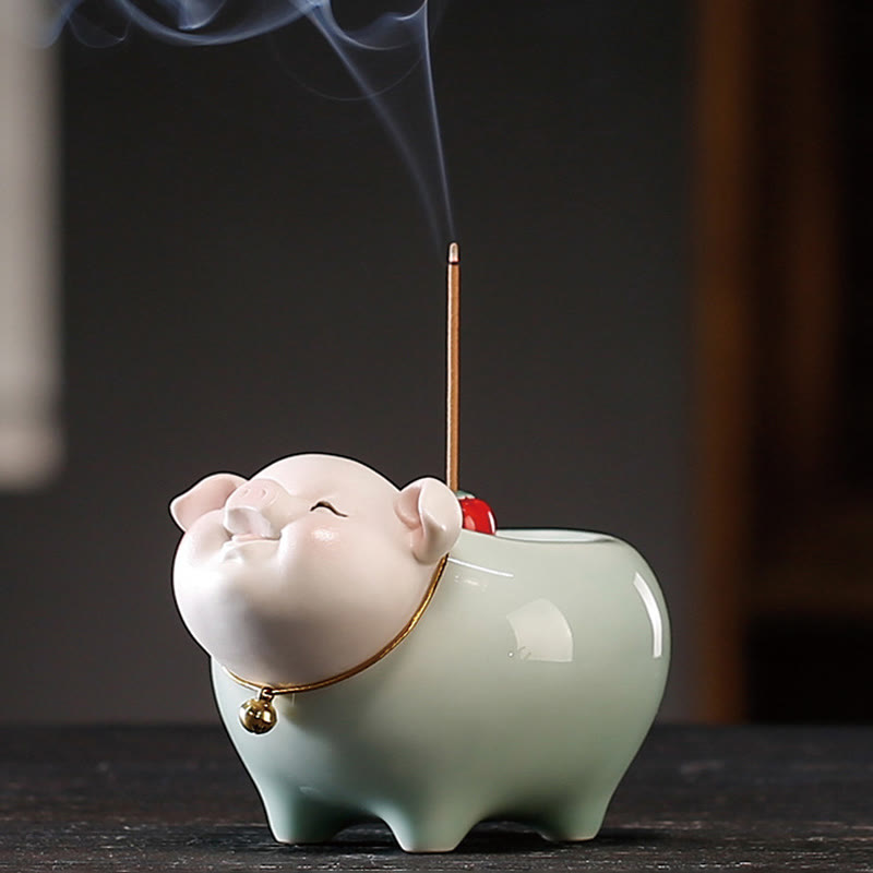Ceramic Little Pig Incense Burner – Pink-faced pig with gold bell, lit incense curling smoke