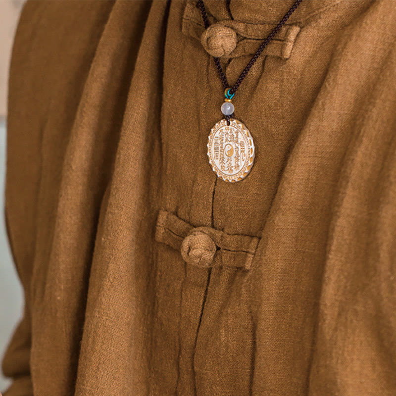 Mountain Ghosts Spend Money Yin Yang Bagua De - Protective amulet on traditional brown clothing, yin-yang talisman close-up