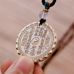 Mountain Ghosts Spend Money Yin Yang Bagua De - Taoist amulet pendant held in hand, gold yin-yang talisman, braided cord