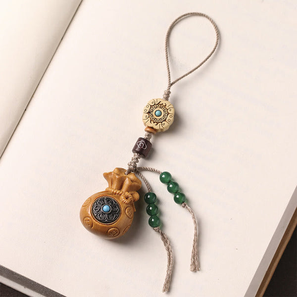 Sandalwood Om Mani Padme Hum Key Chain – tan wood charm on open book, mindful reading