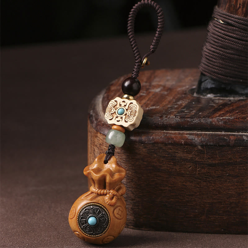 Sandalwood Om Mani Padme Hum Key Chain – tan wood charm on wooden stand, rustic harmony