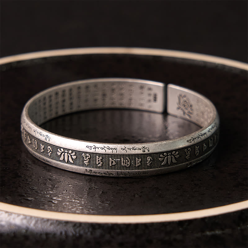 Om Mani Padme Hum Bracelet – Dramatic lighting highlights oxidized silver engraved with Buddhist mantra symbols