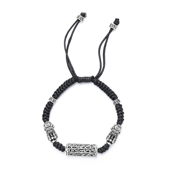 Tibetan PiXiu Bracelet – Isolated black braided bracelet with silver PiXiu and copper mantra cylinder on white