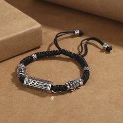 Tibetan PiXiu Bracelet – Black braided cord bracelet with silver PiXiu charms and copper mantra cylinder, top view