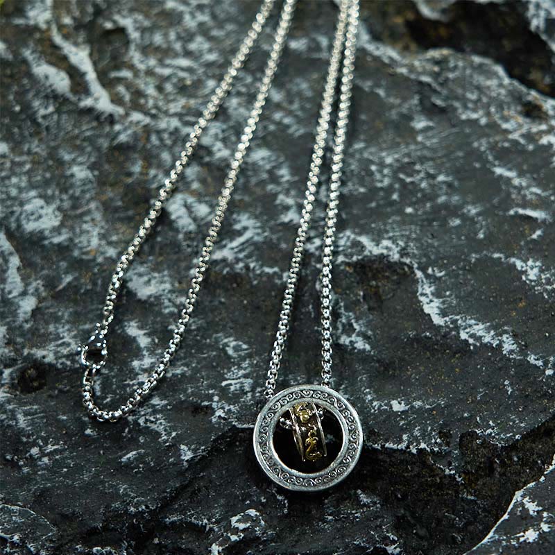 Double Ring PiXiu Necklace – Silver circular pendant with golden PiXiu on chain over dark textured volcanic rock