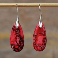 Emperor Stone Healing Crystal Earrings – Vibrant red teardrop stone earrings with dark matrix web patterns and silver hooks hanging on brass rod