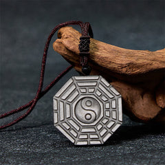 Silver Sheen Obsidian Bagua Yin Yang Pendant on dark stone with driftwood prop, obsidian necklace