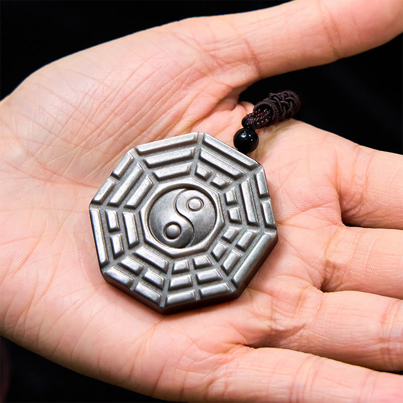 Silver Sheen Obsidian Bagua Yin Yang Pendant resting in palm, carved stone texture close-up