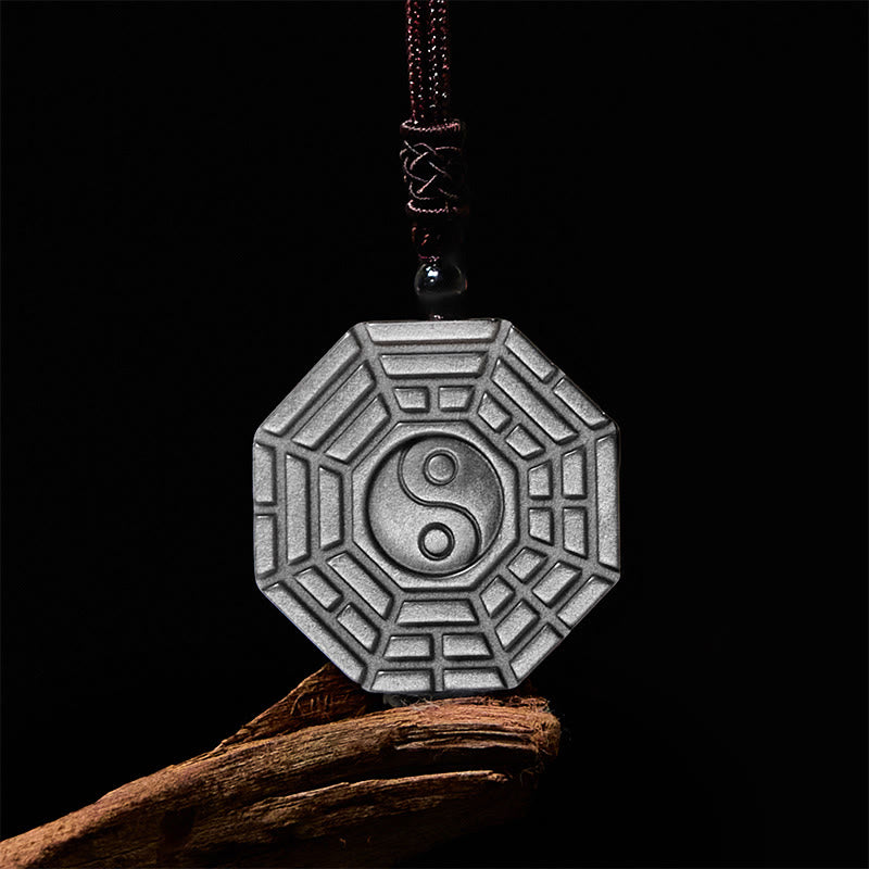 Silver Sheen Obsidian Bagua Yin Yang Pendant on driftwood with dramatic lighting, protective amulet