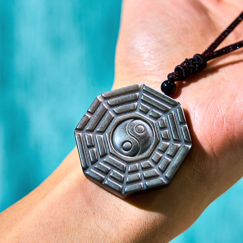 Silver Sheen Obsidian Bagua Yin Yang Pendant on skin with turquoise backdrop, wearable amulet