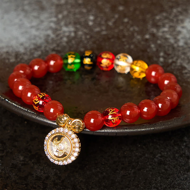 Red Agate Wealth Gods Bracelet – resting on dark stone plate with five colored wealth beads, zen grounding