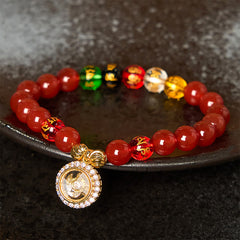 Red Agate Wealth Gods Bracelet – resting on dark stone plate with five colored wealth beads, zen grounding