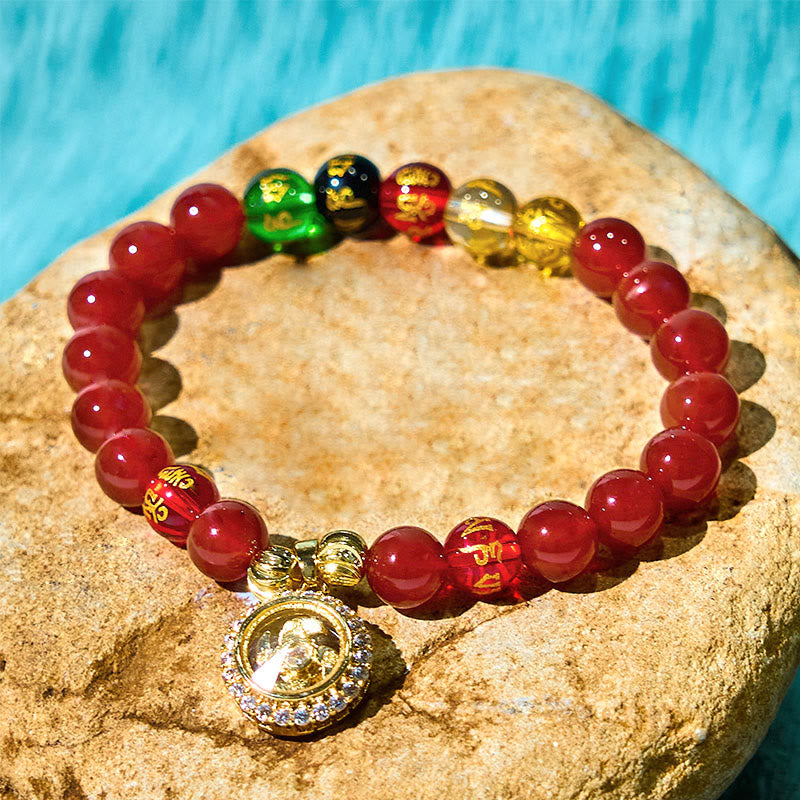 Red Agate Wealth Gods Bracelet – diagonal curve on natural stone with turquoise backdrop, grounding energy