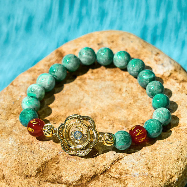 Natural Jade Om Mani Padme Hum Bracelet – Laid on natural stone with turquoise backdrop, gold charm detail